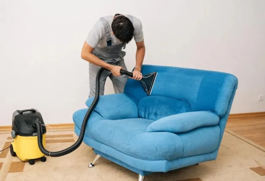 Técnico limpiando una poltrona azul con máquina de inyección y extracción